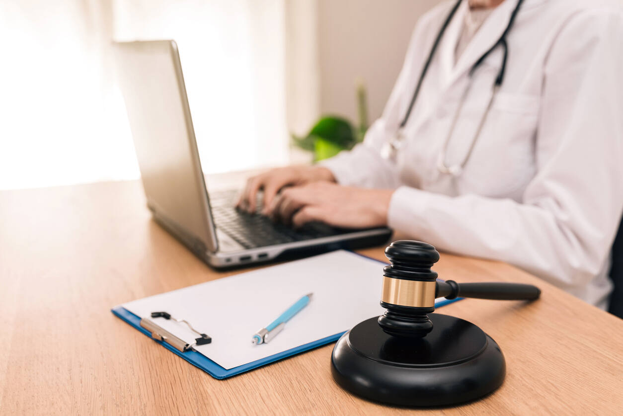 Medical professional or lawyer working on a computer with a gavel nearby, representing legal assistance for Veterans Affairs workers' compensation claims.