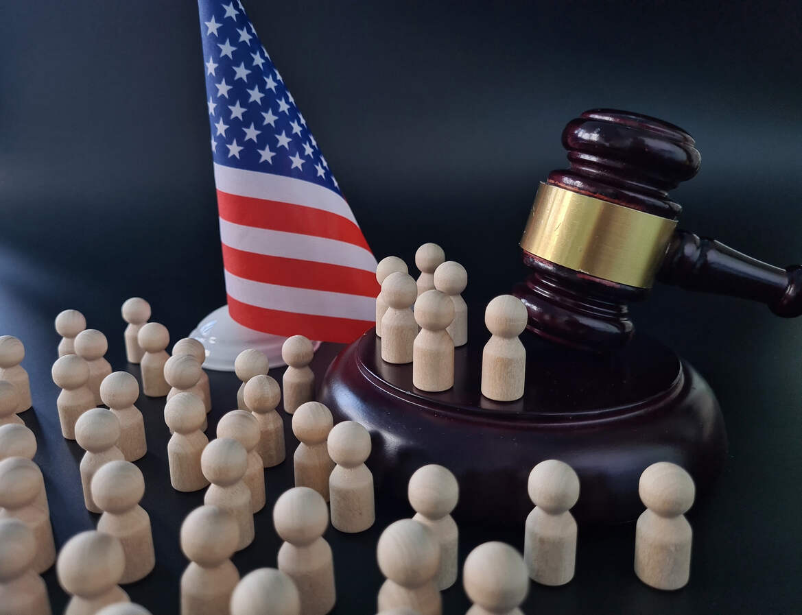 An American flag next to a judge's gavel and numerous wooden people figures, symbolizing federal workers' compensation law.